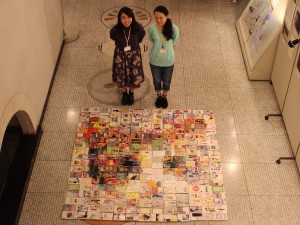 9/25に行ったプレ開催でお披露目された250冊の文庫本を用いたモザイクアート。企画した慶應大学1年の本蔵 紅奈さん（右）、神奈川大学3年の福岡 麻里さん（左）